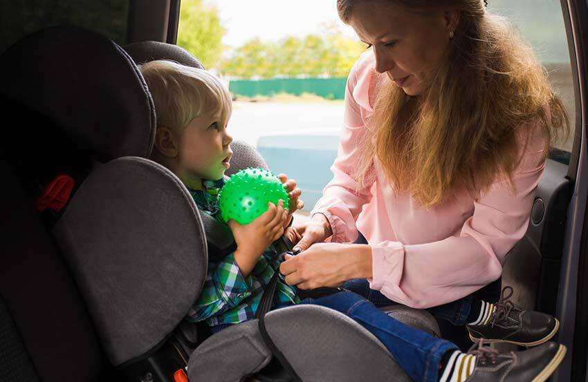 Woman strapping a child into a car seat