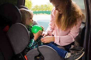 Woman strapping a child into a car seat