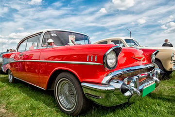 A red classic Chevrolet parked on grass at a car show