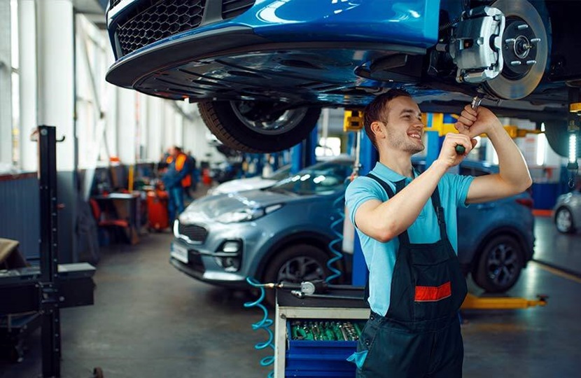 mechanic stood underneath a car repairing it