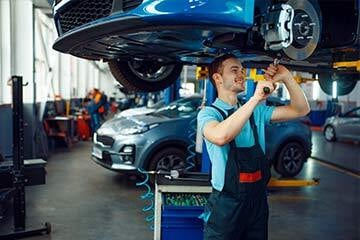 mechanic stood underneath a car repairing it