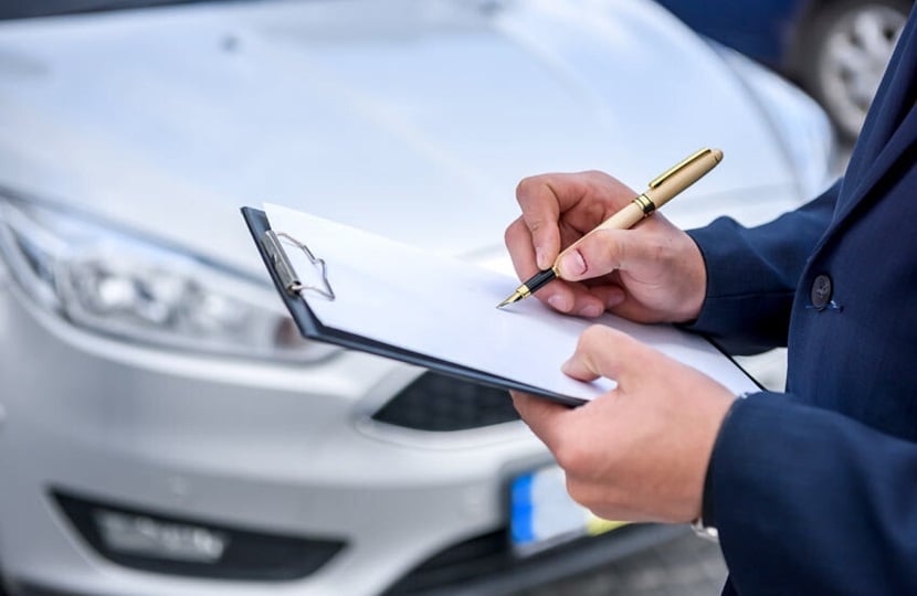 person standing in front of a car with a clipboard and pen