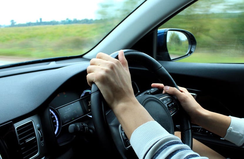 person driving with their hands on the steering wheel