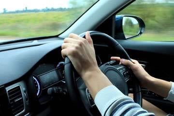 person driving with their hands on the steering wheel