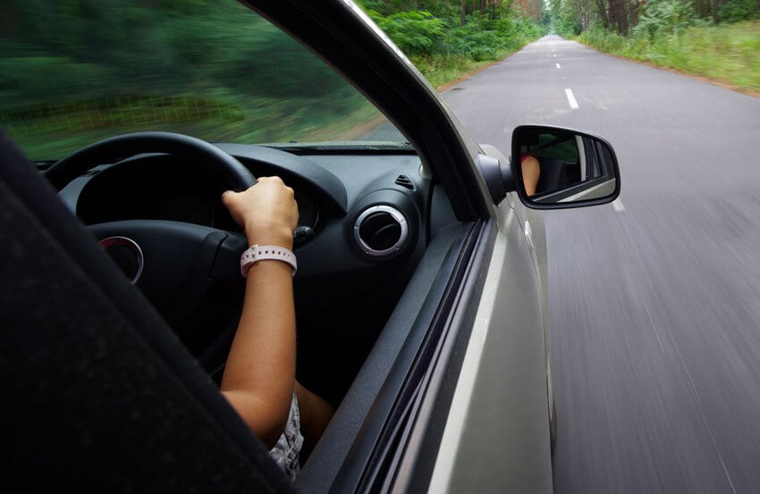 person driving a car with their hands on the steering wheel