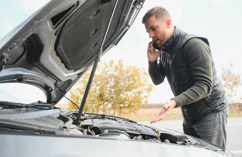 a man on the phone with his car bonnet up