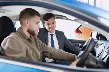 person sat in a car with a salesperson