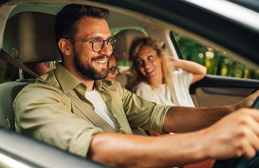 Shot taken from the side of a man driving with a woman in the passenger seat