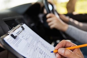 A person writing on a notepad in a car