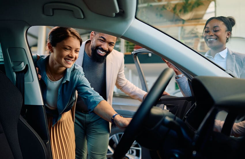 two people looking inside a car at a dealership