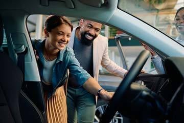 two people looking inside a car at a dealership