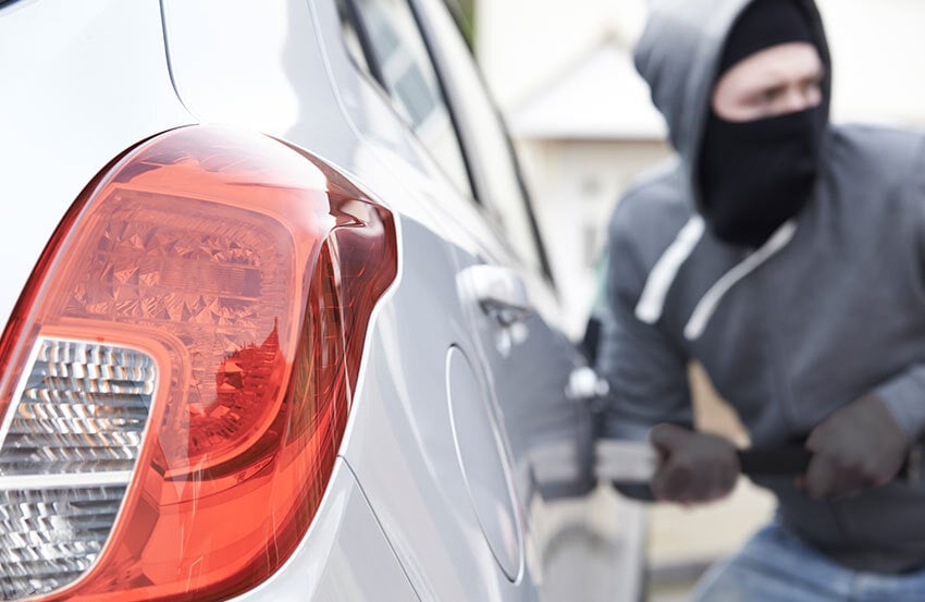 person with a mask on breaking into a car