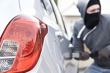 person with a mask on breaking into a car