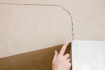 Hand pointing to a crack in the wall