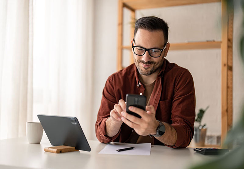 man using his phone at his desk