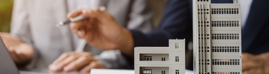 Feature image with model buildings in front of two people sat at a desk