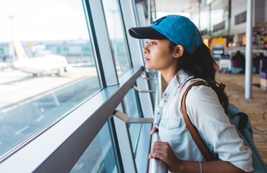 Woman looking out the window at an airport.