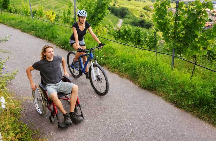 A man in a wheelchair with a woman on a bike.