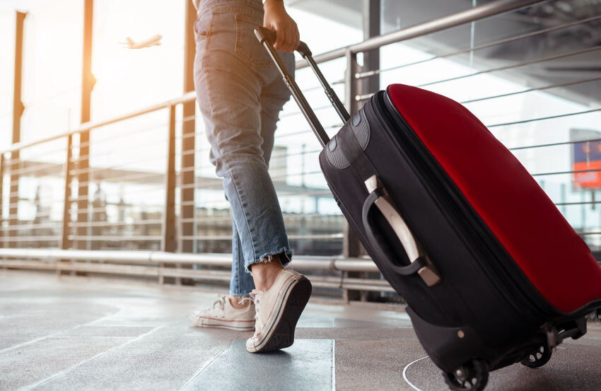 Person walking through an airport with a suitcase.