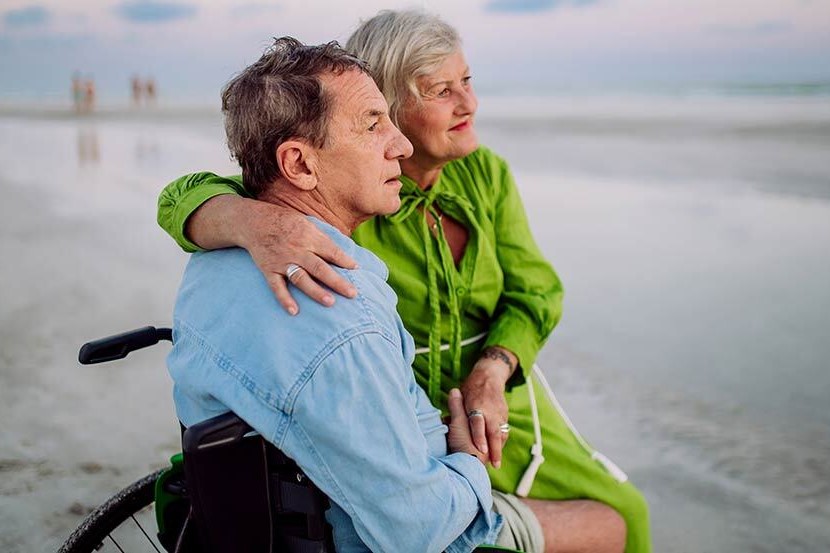 man in wheelchair looking out across beach