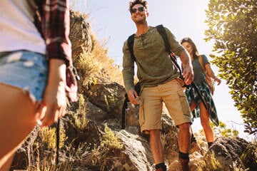 people trekking outdoors with backpacks on