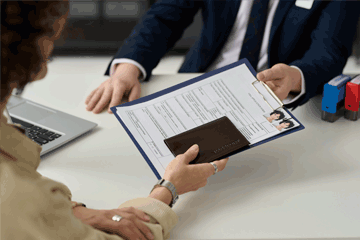 A woman handing documents to a man in a suit