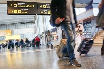 person walking through an airport with a suitcase