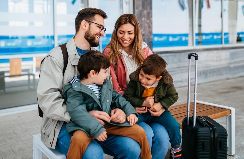 family sat down at an airport with their luggage