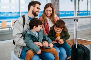 a family sat in an airport with suitcases